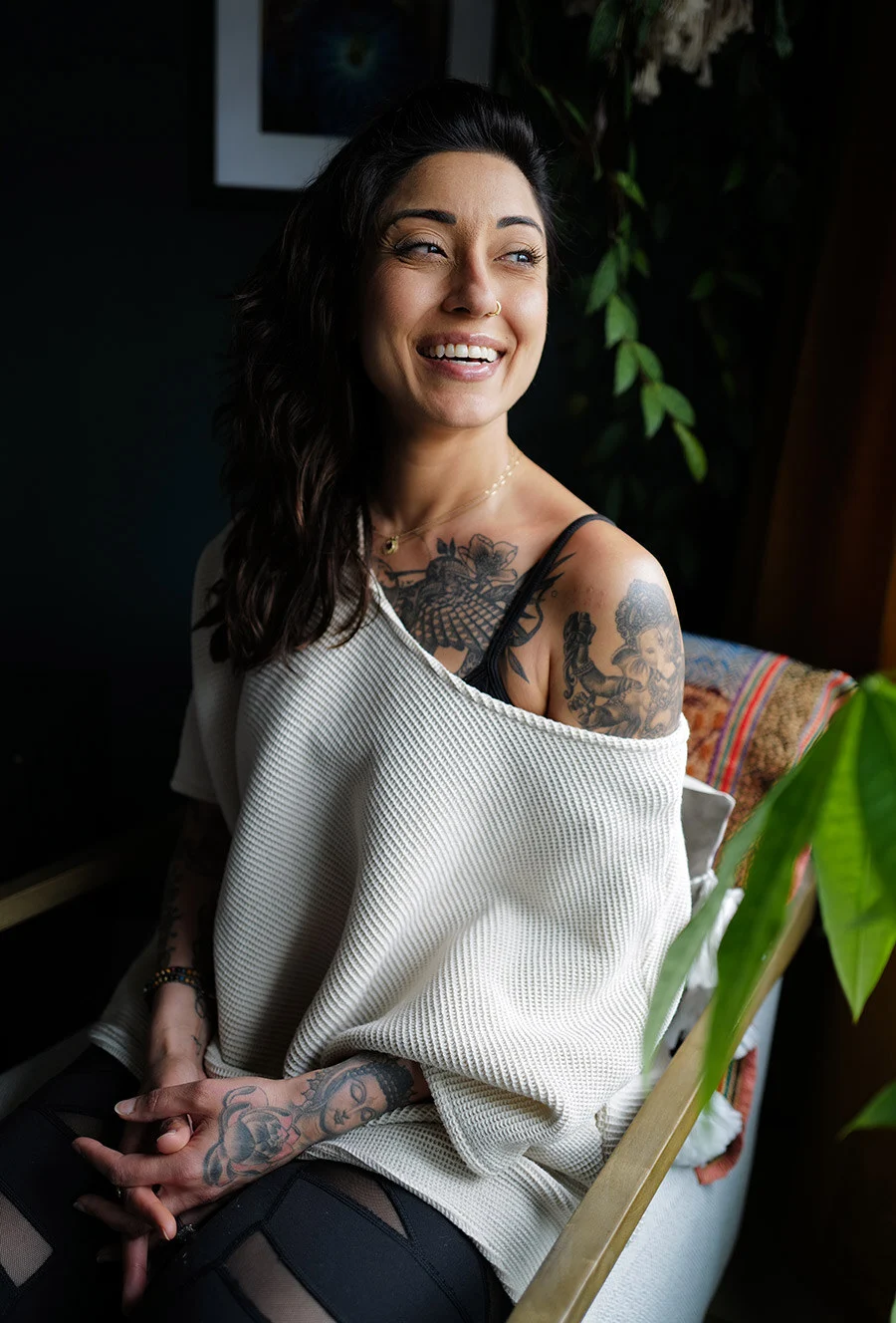 Ruby Fremon seated indoors in a cream knit top, laughing and looking off camera.